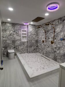 Luxury marble bathroom remodel in Jacksonville, FL with LED lighting and gold shower fixtures by New Empire