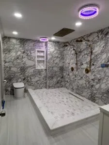 Luxury marble bathroom remodel in Jacksonville, FL with LED lighting and gold shower fixtures by New Empire
